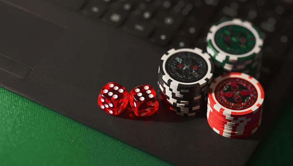 alcune fishes da casino ordinate per colore e un paio di dadi da gioco su una tastiera per pc