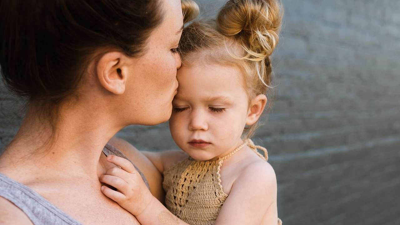 primo piano di una mamma con la figlia piccola in braccio