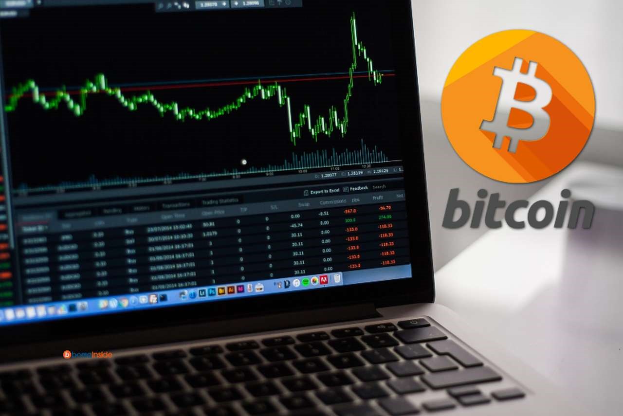 Un laptop con alcuni grafici sull'andamento dei prezzi e il logo di Bitcoin