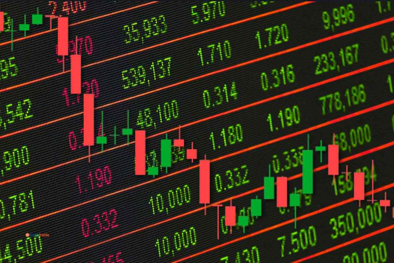 Il tabellone con l'andamento dei titoli in Borsa con un grafico a candele in sovrimpressione