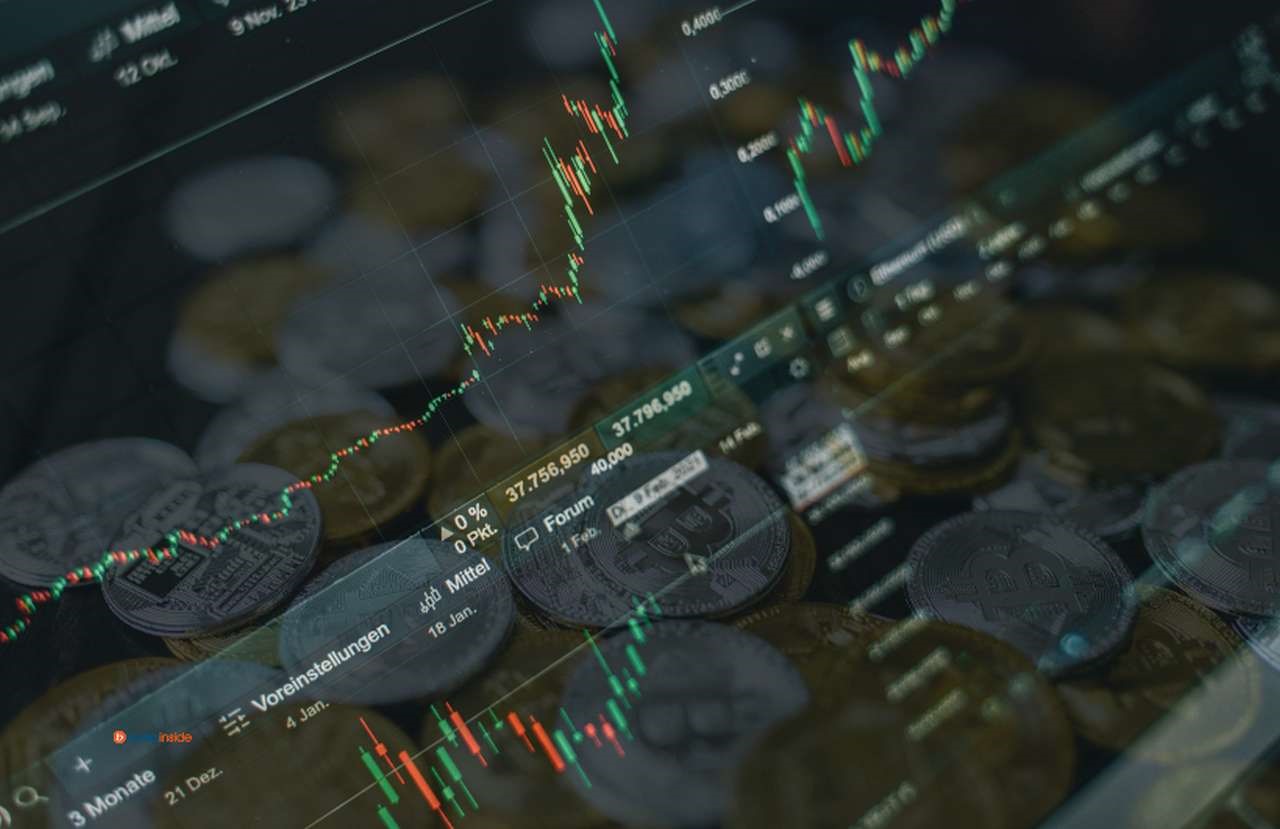 Alcuni grafici a candele con delle monete di Bitcoin d'oro e di argento in trasparenza