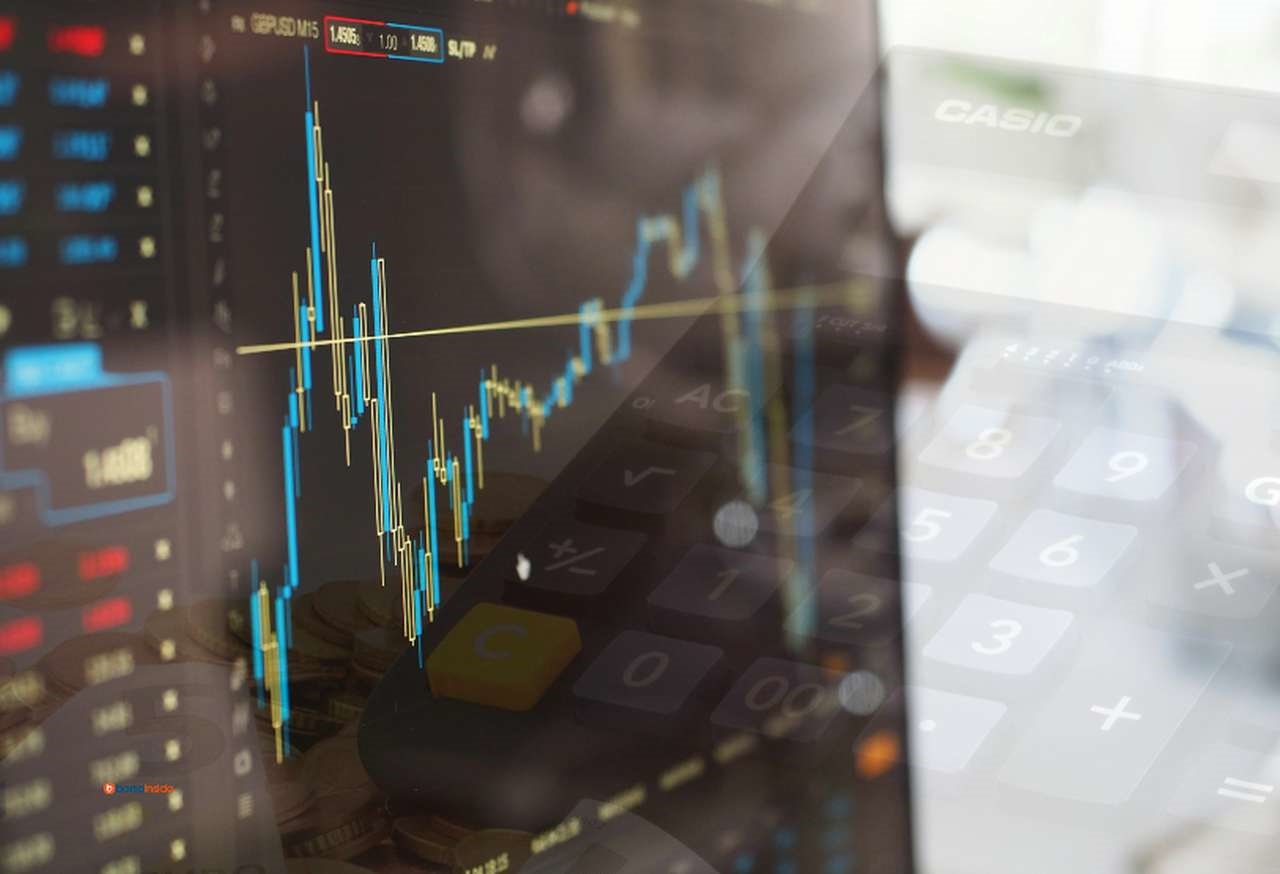 Alcuni grafici a candele su uno schermo nero e una calcolatrice che si intravede in trasparenza